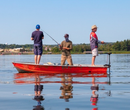 Three men in a red boat are fishing